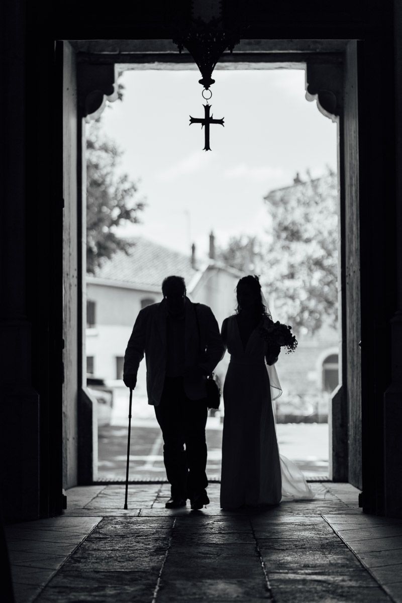 Silhouette d'une mariée à l'entrée d'une église, au bras de son père.