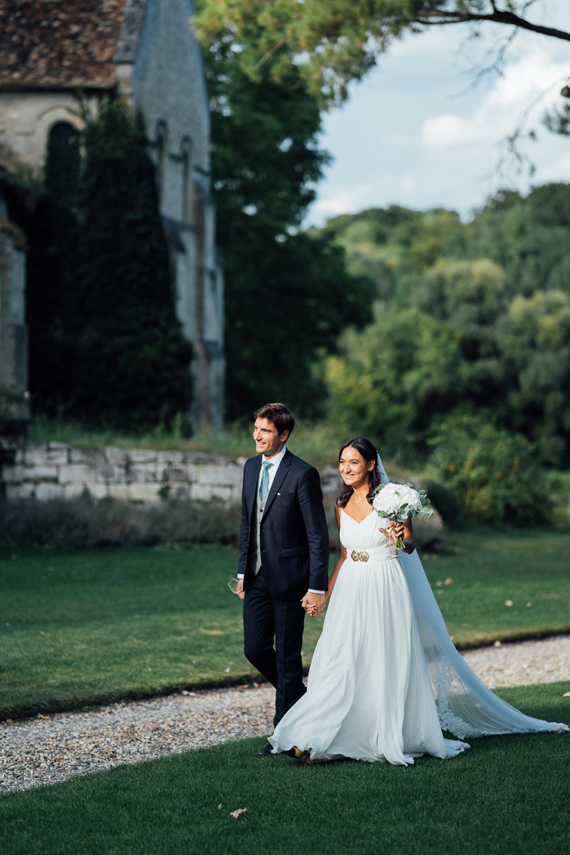 Un couple de mariés heureux marchant main dans la main près d'une église historique.