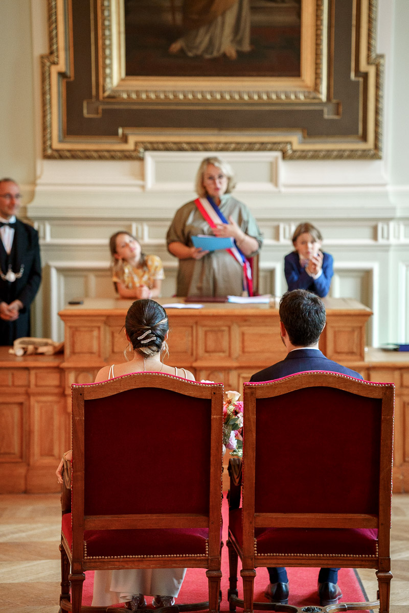 Un couple de mariés assis devant l'officier de mairie pendant leur cérémonie civile.