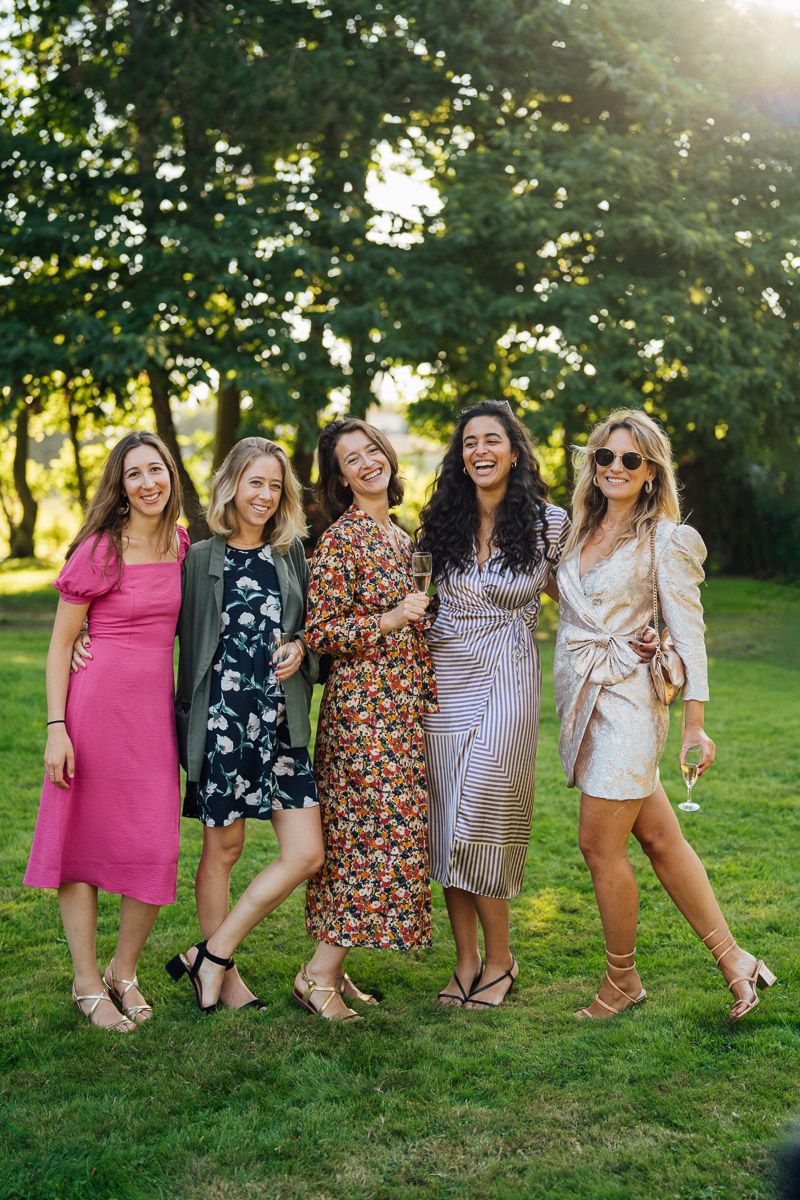 Groupe de femmes élégantes célébrant dans un jardin ensoleillé.